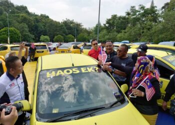 PANDAK AHMAD memasang Jalur Gemilang pada kenderaan yang melakukan formasi berbentuk Jalur Gemilang terbesar di Sireh Park, Iskandar Puteri, semalam.