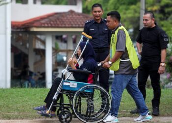 PETUGAS SPR membantu seorang anggota polis dalam proses undi awal di IPD Sepang. - UTUSAN/FAISOL MUSTAFA