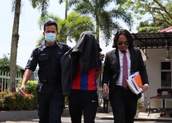 ANGGOTA polis mengiringi seorang doktor yang dituduh melakukan amang seksual dan menghasilkan pornografi gambar terhadap enam kanak-kanak di Mahkamah Sesyen Kemaman, hari ini. - UTUSAN/NIK NUR IZZATUL HAZWANI NIK ADNAN