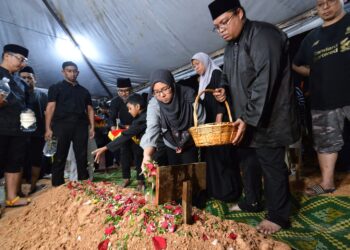 SITI Aisyah Mohd. Roslan menabur bunga di pusara suaminya, Allahyarham Leftenan Komander Mohammad Amirulfaris Mohd. Marzukhi yang selamat dikebumikan di Tanah Perkuburan Islam Forest Heights, Senawang, Seremban, malam ini.-UTUSAN/MOHD. SHAHJEHAN MAAMIN.
