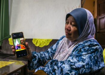 NORYANI Tamadun menunjukkan gambar terakhir bersama arwah adiknya, Muhammad Faisol (baju oren) yang terkorban dalam nahas helikopter di Pangkalan TLDM Lumut ketika ditemui di Kampung Tanjung, Sik semalam.  – UTUSAN/SHAHIR NOORDIN