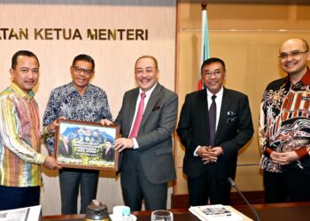 HAJIJI Noor (tengah) menyampaikan cenderamata kepada Ruji Ubi (kiri) sambil disaksikan oleh Saifuddin Nasution Ismail (dua kiri) di Kota Kinabalu semalam.