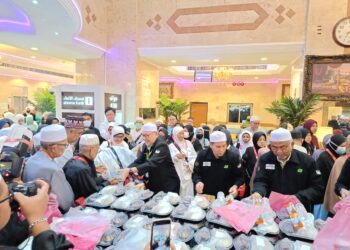 SYED SALEH (tengah) mengedarkan pek sarapan kepada kumpulan jemaah haji yang menginap Maktab 79 dan 80 di Mekah hari ini. - UTUSAN/AMREE AHMAD