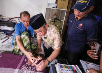 Menteri di Jabatan Perdana Menteri (Hal Ehwal Agama Islam), Datuk Mohd. Naim Mokhtar (tengah) dan Pemangku Ketua Pegawai Eksekutif Majlis Agama Islam Wilayah Persekutuan (MAIWP), Datuk Mohd. Nizam Yahya melihat keadaan kaki penerima bantuan, Jamal Sulaiman dalam Program Ziarah Asnaf Siri ke-7 2024 di PPR Beringin, Jinjang Utara di sini, semalam.