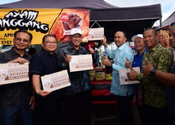 MOHD. JAFNI Md. Shukor (tengah) meletakkan papan tanda peringatan sempena  Sesi Libat Urus Kempen Hargai Makanan Elak Pembaziran di Bazar Ramadan, Jalan Merbau, Kulai, Johor, semalam.-UTUSAN/BAAZLAN IBRAHIM