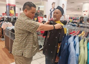 PENASIHAT Rumah Warga Emas Taman Komuniti Bukit Larang, Datuk Akramuddin Abd. Aziz mengenakan baju baharu kepada Basiron Mohd. Ali di sebuah pusat membeli-belah di Melaka.