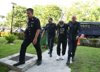 NG Kok Yeow (dua dari kanan) diiringi tiga anggota polis ketika tiba di Mahkamah Majistret Balik Pulau, Pulau Pinang semalam.