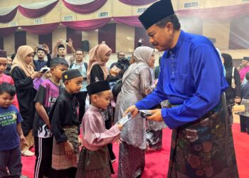 HAMZAH Ahmad (kanan) mengagihkan duit raya kepada kanak-kanak pada Majlis Sambutan Hari Raya Aidilfitri PDRM Kontinjen Pulau Pinang di Kepala Batas, Pulau Pinang malam tadi.-UTUSAN/SITI NUR MAS ERAH AMRAN