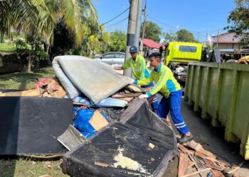 PARA pekerja pembersihan mengutip sampah yang kebanyakan terdiri daripada barangan rosak akibat banjir di sekitar Kangar, Perlis semalam. – UTUSAN/MOHD. HAFIZ ABD. MUTALIB