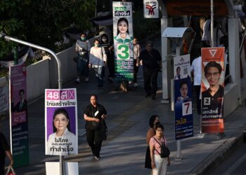 ORANG ramai berjalan melepasi poster kempen menjelang pilihan raya umum di Bangkok.- AFP