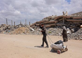 DUA penduduk berjalan di tepi runtuhan bangunan di uata Gaza, 6 Mei lalu. - AFP