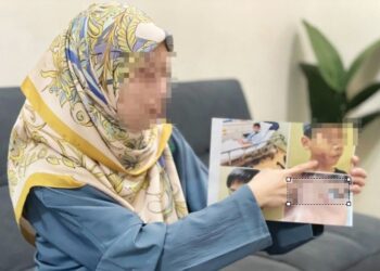 FATIN menunjukkan gambar anak lelakinya yang mengalami tiga kecederaan dipercayai akibat dibuli oleh murid sebuah sekolah di Jitra. 
– UTUSAN/JAMLIAH ABDULLAH