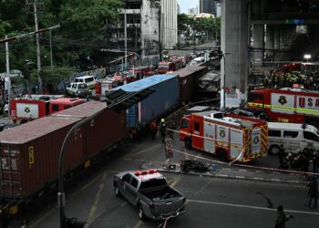 Anggota polis, petugas penyelamat dan anggota bomba berada di lokasi pelanggaran tren dengan sebuah bas di bawah stesen Airport Rail Makkasan, Bangkok semalam. - AFP