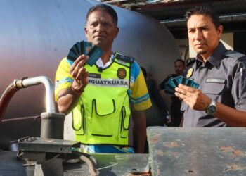 S. JEGAN (kiri) menunjukkan sebahagian daripada kad fleet yang dijumpai susulan serbuan ke atas sebuah stor pemborong berlesen di Nibong Tebal, Pulau Pinang hari ini.-UTUSAN/DANIAL SAAD