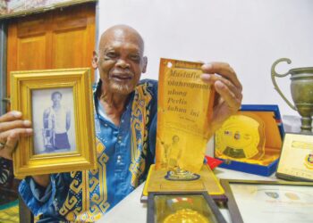 MUSTAFFA Ibrahim atau lebih dikenali sebagai Cikgu Pa menunjukkan gambar dan piala diraih sepanjang bergelar pendidik dan selepas bersara di rumahnya di Taman Ira, Kangar, Perlis semalam. 
– UTUSAN/IZLIZAN OTHMAN