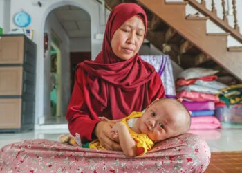 MUHAMMAD Rayqal Rizqi Mohd. Fadir dipangku Siti Zakiah Mamat 
di rumah mereka di Kampung Rhu Dua, Rusila, Marang, Terengganu. 
– UTUSAN/PUQTRA HAIRRY