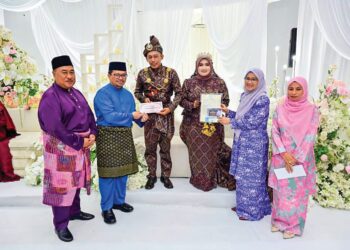 SABARIAH Saidan (dua, kanan) menyampaikan sumbangan kepada pasangan pengantin baharu peringkat Parlimen Kuala Krau di Balora Mastika Jengka di Maran, Pahang.