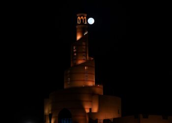 ‘Bulan Biru’  terbit di langit di belakang menara yang diterangi cahaya di Masjid Al-Fanar, Doha, Qatar, Ahad lalu. - AFP