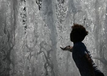 SEORANG budak menyentuh air pancuran di Berlin. - AFP