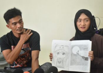 NORASIKIN Hasin (kanan) dan Muhamad Abdul Hadi Mohd Fauzi (kiri) menunjukkan lakaran lukisan yang ditemui dalam diari anaknya yang didakwa menjadi mangsa buli di kediamannya di Chuping, Padang Besar, Perlis hari ini-UTUSAN/ASYRAF MUHAMMAD