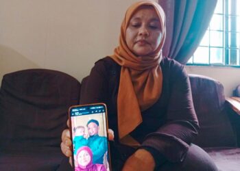 SURIANA Mohamed menunjukkan gambar Allahyarham Saifullah Isyraf yang meninggal dunia Isnin lalu selepas terlibat dalam kemalangan di Rusila, Marang. - UTUSAN / ERMA YUSNIDA JUSOH