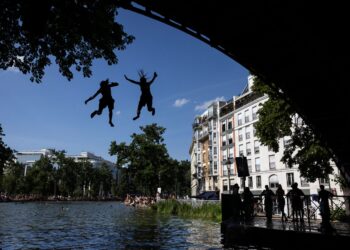 DUA orang terjun untuk menyejukkan badan dari sebuah jambatan di Paris. - AFP