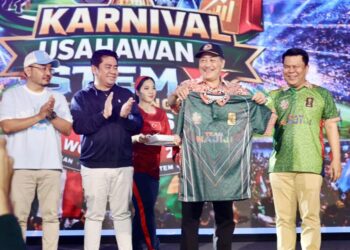 Hajiji Noor (dua, kanan) menerima jersi bola sepak sebagai cenderamata kenangan selepas merasmikan Karnival Usahawan dan STEM X Challenge sempena perlawanan akhir Piala Dunia 2026 di Pusat Kebudayaan Bajau Sama Sabah, Lok Batik, malam tadi. - UTUSAN/HARDY JOE