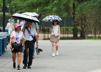 BEBERAPA pelancong menggunakan payung di Washington kelmarin. - AFP