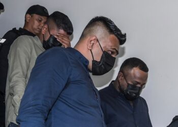 TIGA individu yang didakwa melakukan perbuatan khianat dengan api membabitkan tiga buah kereta milik isteri aktivis, Cikgu Chandra ketika diiringi pegawai polis di Mahkamah Petaling Jaya, di sini hari ini. - UTUSAN/SYAKIR RADIN