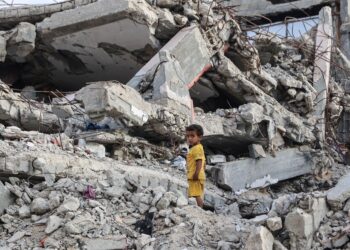 SEORANG kanak-kanak berdiri di celah runtuhan bangunan di Gaza. - AFP
