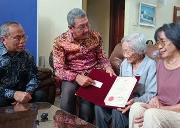 WAN Ahmad Dahalan Abdul Aziz (kiri) menyampaikan kad pesara baharu kepada Ong Siew Choon pada Program Santuni Pesara Bersama Ketua Pengarah Perkhidmatan di Seremban hari ini.-UTUSAN/NAZARUDIN SHAHARI