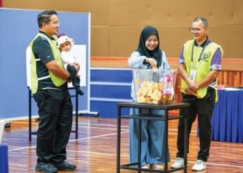 PETUGAS Suruhanjaya Pilihan Raya (SPR) melihat isteri anggota tentera memasukkan kertas undi awal ke dalam kotak undi sempena Pilihan Raya Negeri (PRN) Negeri Sembilan di Dewan Angkasaraya Pangkalan TUDM Sendayan, Seremban, semalam. - UTUSAN/ISKANDAR ISHAK
