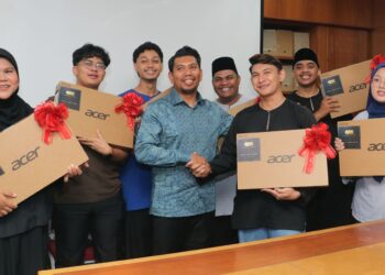 Azman (tengah) menyerahkan laptop kepada pelajar terpilih dalam Program Pengurusan Hartanah UiTM Shah Alam, hari ini.