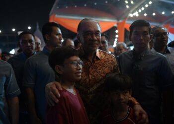 ANWAR Ibrahim menyantuni kanak-kanak pada Majlis Perasmian Program Santai Perantau Sempena 70 Tahun FELDA di Jalan Maktab, Kuala Lumpur hari ini. - UTUSAN/SYAKIR RADIN