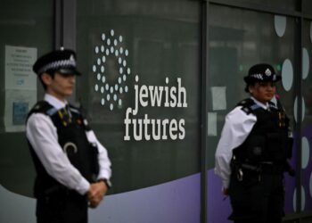DUA anggota polis berdiri di hadapan sebuah premis yang sebelum ini digunakan oleh syarikat Jewish Futures di Hendon, utara London. - AFP