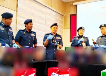 MOHD. NADZRI (tengah) menunjukkan minuman keras dan bir yang dirampas oleh JKDM Perak di Pejabat Kastam JKDM Teluk Intan, hari ini.