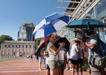 SEBAHAGIAN orang menggunakan payung akibat cuaca panas di Philadelphia. - AFP