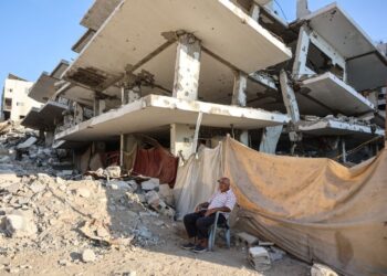 SEORANG lelaki duduk di tepi sebuah bangunan musnah akibat serangan Israel di Gaza. - AFP
