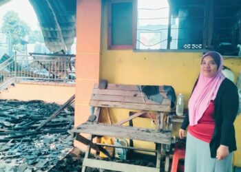 SITI Nor Azizan Mustafa menunjukkan besi tingkap yang diumpil untuk menarik adiknya yang terperangkap dalam kebakaran di Kampung Kubu Telaga Bata, Tumpat, Kelantan. – UTUSAN/ ROHANA ISMAIL