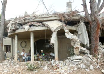 DUA lelaki duduk di rumah yang musnah akibat serangan Israel di selatan Lubnan. - AFP