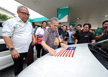 KUALA LUMPUR 9 OGOS 2026 - Menteri Komunikasi, Datuk Seri Fahmi Fadzil (tiga kiri) memasang magnet Jalur Gemilang pada sebuah kenderaan orang awam pada Program Ekspresi Jalur Gemilang JAPEN@PETRONAS di Stesen PETRONAS NPE Pantai Dalam di sini hari ini. 
Turut sama, Ketua Pengarah Jabatan Penerangan Malaysia, Erwin Khairul Ahmad (kiri). GAMBAR: FARIZ RUSADIO / PEMBERITA: DEWI