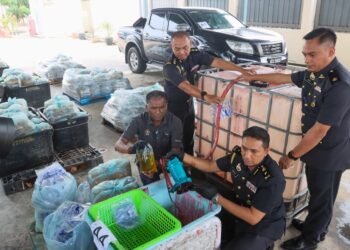 S. JEGAN (duduk, kiri) menunjukkan sebahagian daripada barang yang digunakan untuk memproses minyak masak bersubsidi kepada minyak terpakai ketika sidang akhbar di Stor Ekshibit KPDN di Bukit Mertajam, Pulau Pinang hari ini.-UTUSAN/DANIAL SAAD
