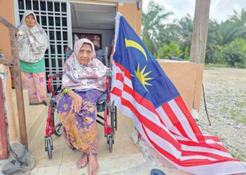 ATIMAH Narijan berkerusi roda mengibarkan Jalur Gemilang di rumahnya di Kampung Tanjung Sari, Pasir Salak, Perak.  
– MINGGUAN/AIN SAFRE BIDIN