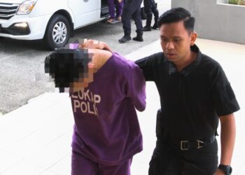TERTUDUH semasa dibawa polis untuk menghadiri prosiding perbicaraan di Mahkamah Sesyen, Pasir Mas, Kelantan.