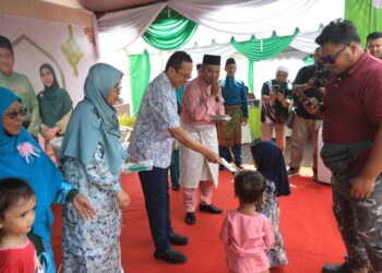 AHMAD Samsuri Mokhtar menyampaikan sumbangan duit raya kepada kanak-kanak yang hadir pada Majlis Hari Raya DUN Rhu Rendang di Pantai Peranginan Kelulut, Marang, hari ini. - UTUSAN/PUQTRA HAIRRY ROSLI