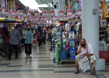 Seorang lelaki warga emas memegang akhbar di Lebuh India. Kuching. yang dihiasi dengan poster calon Gabungan Parti Sarawak (GPS), Wee Hock Seng bagi DUN Padungan sempena Pilihan Raya Negeri Sarawak, semalam. - UTUSAN/ MUHAMAD IQBAL ROSLI
