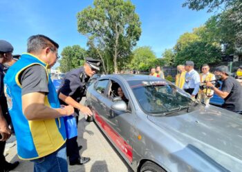 AHMAD Shukri Mat Akhir bertanyakan khabar dan mengedar buah tangan kepada pengguna jalan raya ketika Program Op Selamat Trafik Kota Setar di Plaza Tol Alor Setar Utara, Alor Setar. -UTUSAN/JAMLIAH ABDULLAH