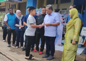 AMINUDDIN Harun menyampaikan Kad Anak iaitu kad bagi memberikan kemudahan rawatan dan ubatan percuma di klinik kepada salah seorang kanak-kanak penerima pada Majlis Pelancaran Kad Anak Peringkat Negeri Sembilan di Klinik Dr. Aizuddin di Senawang, Seremban hari ini.