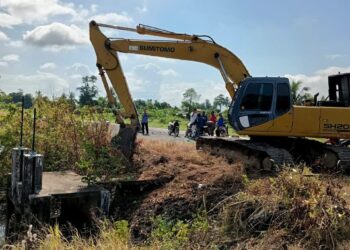 UMNO Bahagian Arau membantu menyediakan jengkaut membersihkan saliran yang tersumbat sekali gus membantu para pesawah untuk memulakan proses tanaman padi di sekitar Simpang Empat dan Sanglang, semalam.- UTUSAN