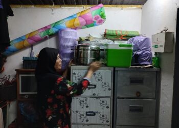 HASNAH Mohd. Rejab  mengemas beberapa barangan penting di tempat tinggi susulan amaran air pasang besar di Kuala Muda, Kota Kuala Muda, Sungai Petani hari ini. - UTUSAN/NUR SYAZWANA MANSOR